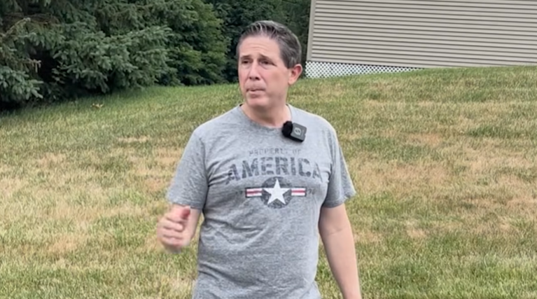 Town Manager Mike Paulhus speaking outdoors with 'Petit 5K Race' captioned on a video screenshot.